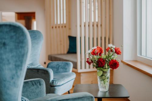 a vase of flowers sitting on a table with chairs at Hotel Berghaus Rosengarten in Nova Levante