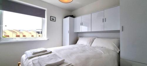 ein weißes Schlafzimmer mit einem Bett und einem Fenster in der Unterkunft 5 Penhale in Perranporth