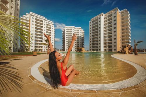 a woman in a red dress sitting in the water at Ground Garden View Apartments in Caesar Resort & SPA, Long Beach in Perivolia tou Trikomou