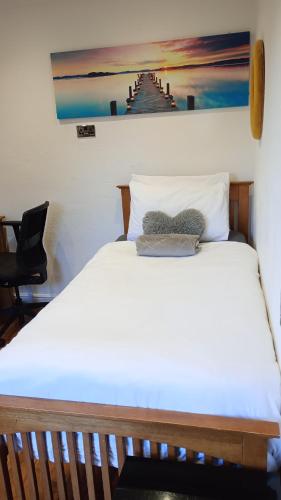 a bedroom with a white bed with a painting on the wall at Number 14 in Ipswich