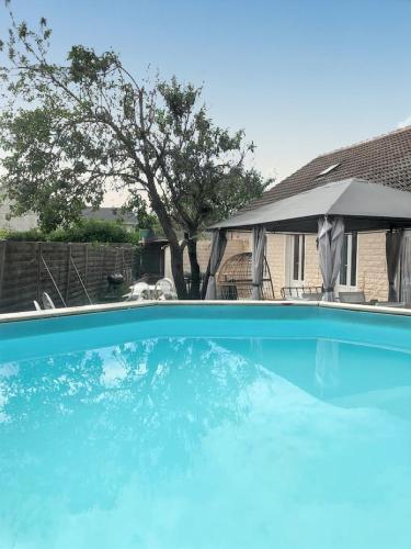 une grande piscine bleue avec un parasol dans l'établissement Villa charmante à Saint-Martin-Longueau avec piscine privée, à Saint-Martin-Longueau