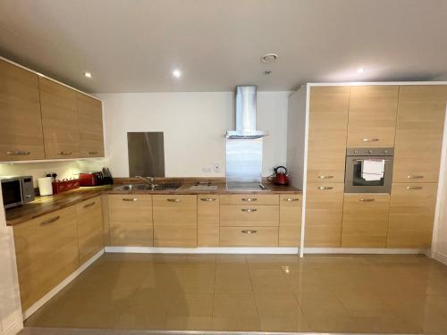 a large kitchen with wooden cabinets and a stove at Blue Sky Apartments @Wallis Square, Farnborough in Farnborough