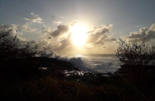a sun setting over the ocean with a waterfall at Chambre Maison Kumba in La Désirade