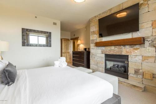 a bedroom with a white bed and a fireplace at Grand Summit Hotel #702 Penthouse Ski-In, Ski-Out Corner Unit in Park City