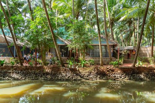 a house in the jungle with a body of water at Palm Trees Ayurvedic Heritage in Patnem