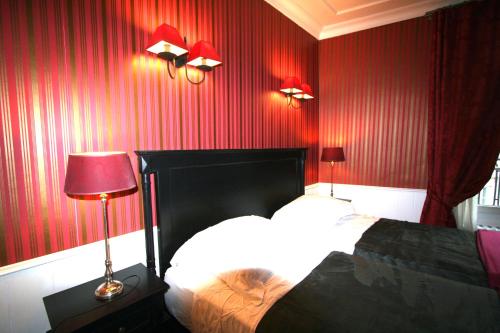 - une chambre avec des murs rouges, un lit et deux lampes dans l'établissement ParisInteriorsRentals - Beautiful Le Marais NOTRE DAME Appartement, à Paris