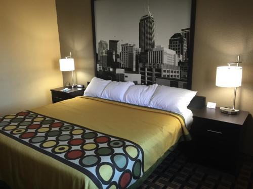 a large bed in a hotel room with a city skyline at Super 8 by Wyndham Terre Haute in Terre Haute