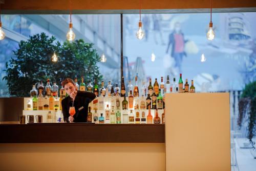a man behind a bar with bottles of alcohol at DoubleTree By Hilton Milan in Milan