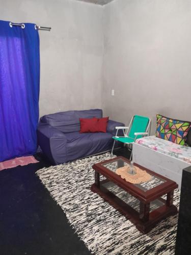 Una sala de estar con un sofá morado y una mesa. en Quintal Compartilhado - Casa Temporada, en Armacao dos Buzios