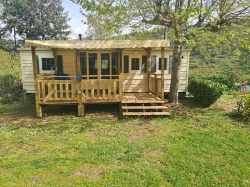 a small yellow tiny house with a porch at Camping La Douce Ardèche in Désaignes
