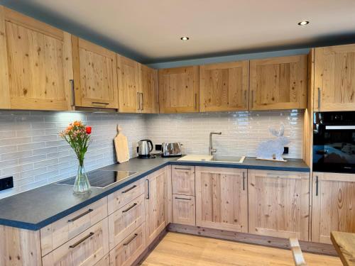 a kitchen with wooden cabinets and a vase of flowers at TONIS cozy Guesthouse by Alpin Charme Apartments in Reith bei Kitzbühel