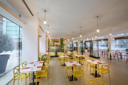 a restaurant with yellow chairs and tables and windows at DoubleTree By Hilton Milan in Milan