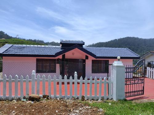 a small pink house with a white fence at Fortune Retreats in Ooty