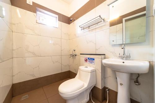 a bathroom with a white toilet and a sink at Fortune Retreats in Ooty