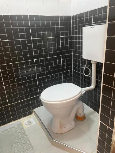 a bathroom with a toilet in a black tiled wall at Nairobi Transit Lounge in Nairobi
