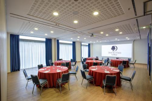 a conference room with red tables and chairs and a screen at DoubleTree By Hilton Milan in Milan