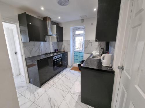 a kitchen with black cabinets and a counter top at Single room Hayes, Heathrow, London, Free parking in Hayes