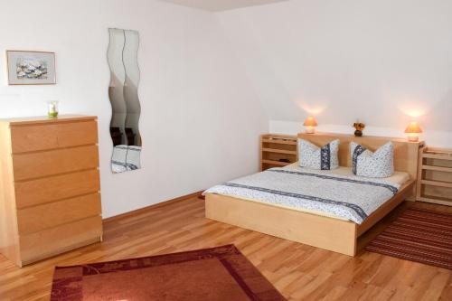 a bedroom with a bed and a dresser at Landhaus im Grünen - Sine Tempore in Grammendorf