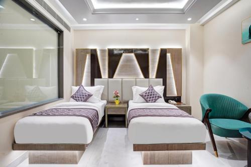a room with three beds and a chair at Gold The Prime Newly Built 2 Mins From Connaught Place and Railway Station in New Delhi