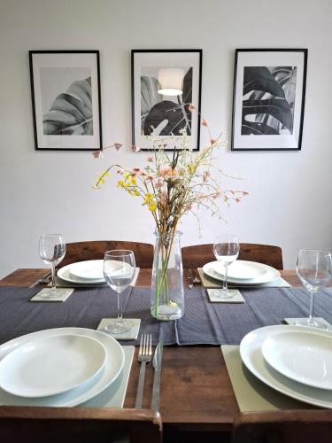 a table with plates and glasses and a vase with flowers at Modern Bright 3 Bedroom House in Lincolnshire