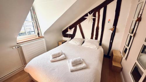 une chambre avec un lit blanc avec deux serviettes dessus dans l'établissement Le Mansart classé 3 étoiles Charme ancien et Havre de paix, à Versailles