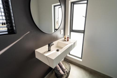 a bathroom with a white sink and a mirror at Leeuwkop Hunting Safaris in Kimberley