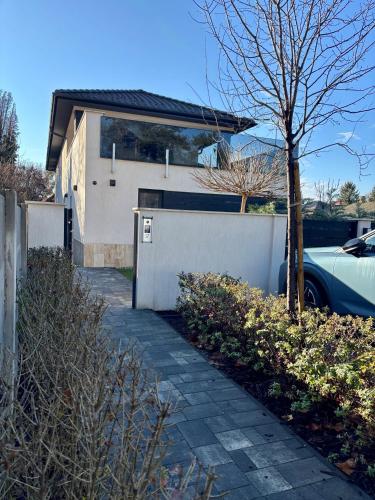 a house with a car parked next to a sidewalk at Pipacs 17 by HelloBalatonlelle in Balatonlelle