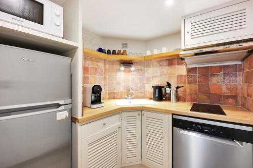 - une petite cuisine avec des placards blancs et des comptoirs en bois dans l'établissement MyKeypers - Deluxe Flat 6P - St Germain des Pres Café de FLORE, à Paris