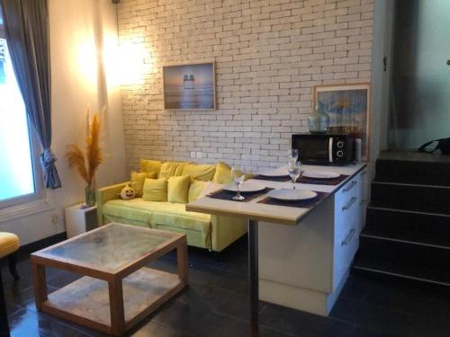 un salon avec un canapé jaune et une table dans l'établissement Appartement avec 2 chambres - Métro 8 Ecole Veterinaire, à Maisons-Alfort