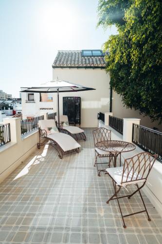 a patio with chairs and an umbrella on a roof at La Fonda Heritage Hotel Luxury, Relais & Châteaux in Marbella