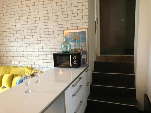 a kitchen counter with two wine glasses and a microwave at Appartement avec 2 chambres - Métro 8 Ecole Veterinaire in Maisons-Alfort