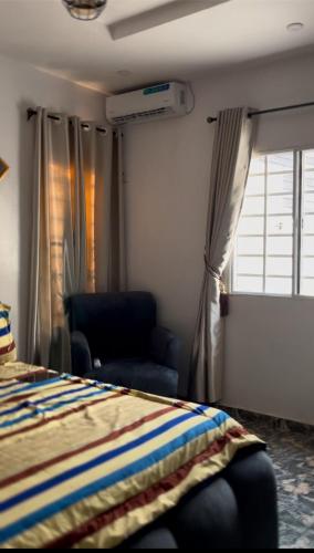 a bedroom with a bed and a chair and a window at Sea-Love Apartment in Ado Ekiti