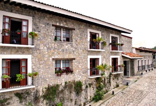 un bâtiment en pierre avec des plantes en pot sur les fenêtres dans l'établissement Hotel Boutique La Casona de Don Porfirio, à Jonotla