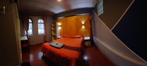a bedroom with a bed with an orange bedspread at EUCALYPTUS POTOSI only dollars or euros are accepted in Potosí