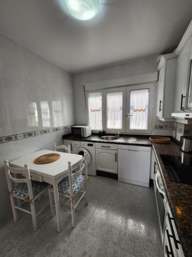 a kitchen with a white table and chairs in it at Laxe Piso Sol - Wifi y Netflix in Laxe