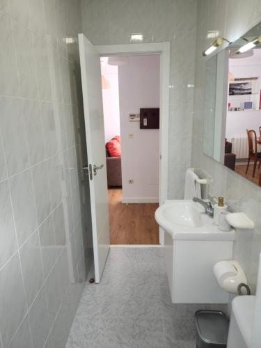 a white bathroom with a sink and a mirror at Laxe Piso Sol - Wifi y Netflix in Laxe