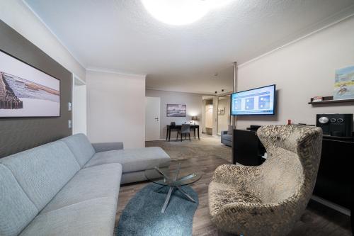 a living room with a couch and a chair and a television at Strandhotel Duhnen in Cuxhaven