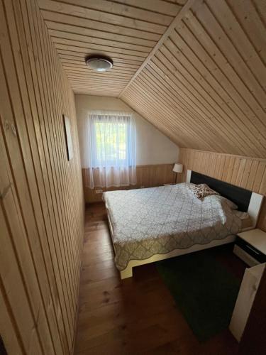 a small bedroom with a bed in a wooden ceiling at Holiday House Strawberry in Druskininkai