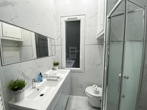 une salle de bain blanche avec un lavabo et une douche dans l'établissement Urban Flat 72 - Pretty 3 Bedroom Flat - Triangle d Or, à Paris