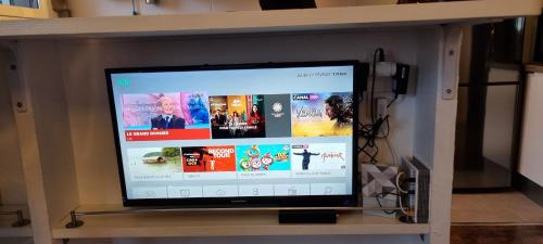 une télévision à écran plat assise sur une étagère. dans l'établissement Appartement avec vue panoramique sur les montagnes, au Bourget-du-Lac