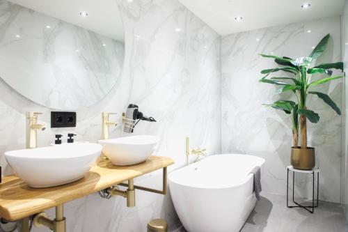 a bathroom with two white sinks and a plant at In de Mid - Prachtige appartementen in hartje Joure in Joure