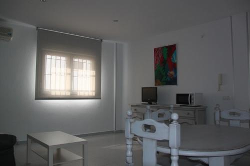 sala de estar con mesa y ventana en Apartamentos El Yunque- Solo Familias, en Conil de la Frontera