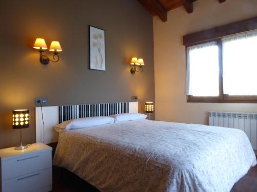 a bedroom with a white bed with two lamps and a window at Sardalla in Ribadesella