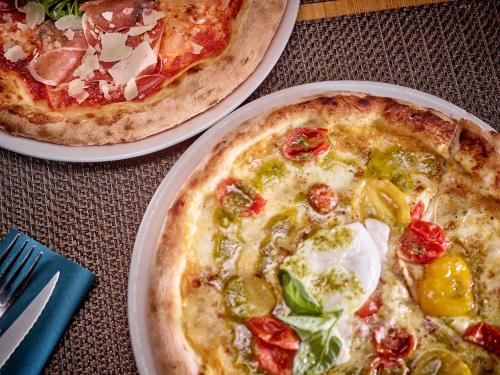 two pizzas sitting on plates on a table at Hotel Europe in Zinal