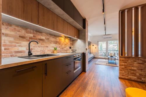 a kitchen with wooden cabinets and a brick wall at Flexible SelfCheckIns 122 - Zagreb - Bedroom - Loggia in Zagreb