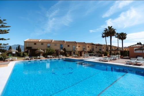 a large swimming pool with palm trees and buildings at Chalet with Sea Views in Fuengirola