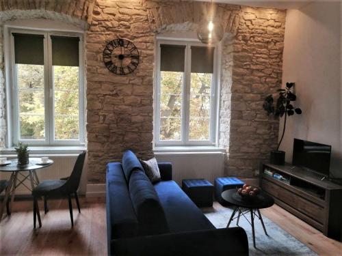 a living room with a blue couch and a stone wall at Biały Kruk Apartamenty vis-a-vis Jasnej Góry 5a in Częstochowa