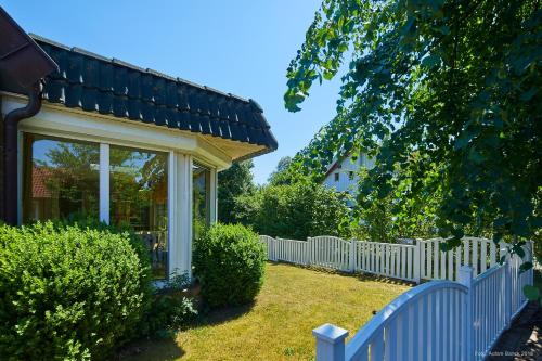 a white picket fence in front of a house at Doppelzimmer mit kleiner Pantryküche Gästehaus Unter den Linden in Mühbrook