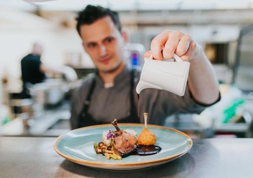 a man holding a piece of paper next to a plate of food at Wellness & Spa Hotel Kaskady in Sliač