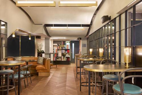 a restaurant with tables and chairs and a couch at Victory House Leicester Square in London
